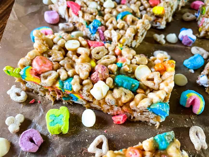 Close up of a Lucky Charms Cereal Bar surrounded by cereal pieces