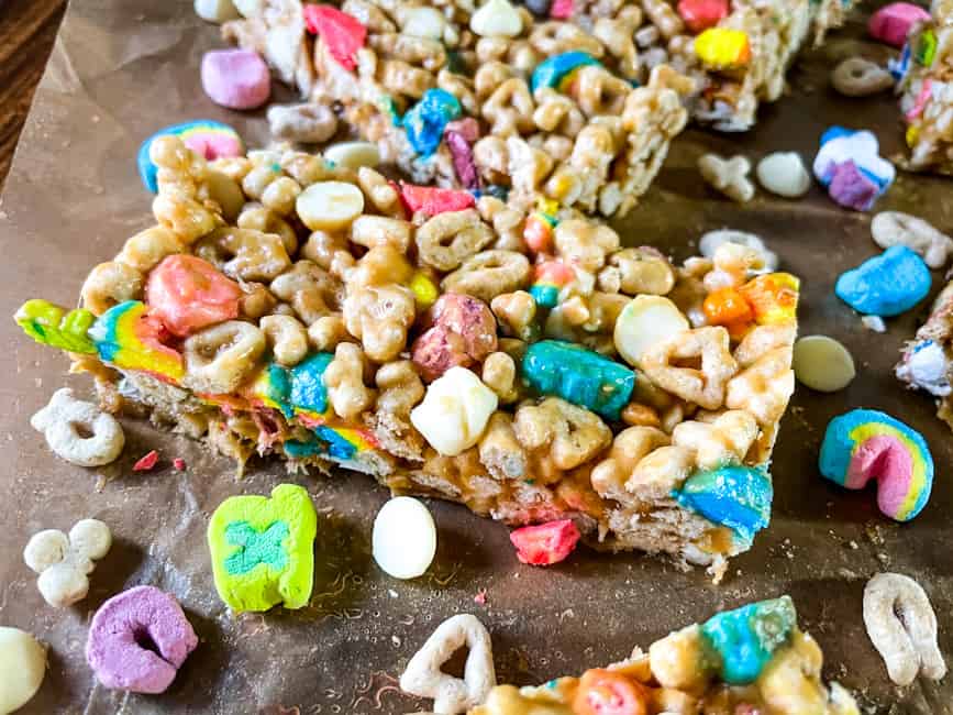 Close up of a Lucky Charms Cereal Bar surrounded by cereal pieces