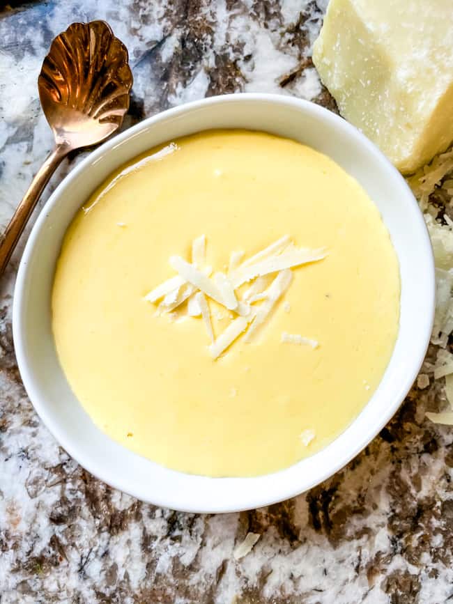 Yellow hollandaise in a white bowl on a counter