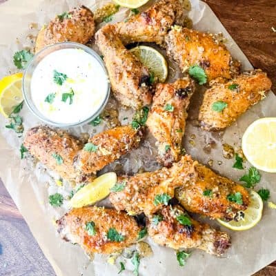 Lemon Pepper Chicken Wings Air Fryer wings scattered on parchment with dipping sauce and lemons