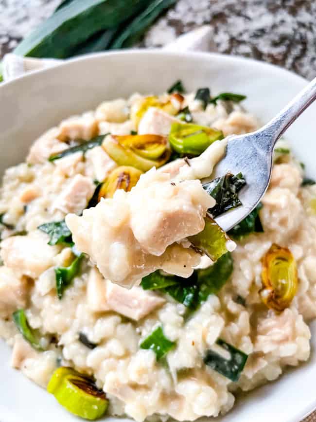 A fork with the creamy rice, over a bowl