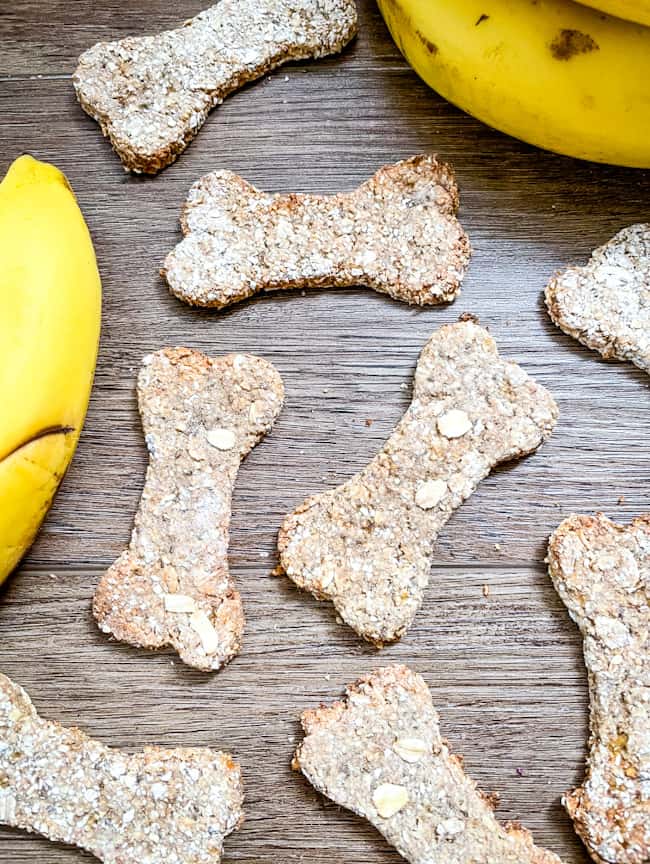 Banana Dog Treats scattered across a wood surface with a couple bananas