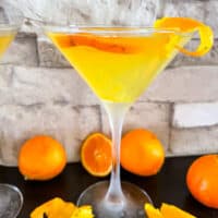 An Orange Martini with oranges around it