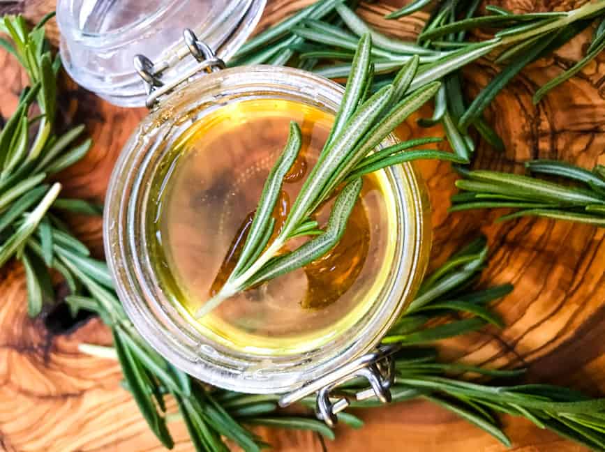 A small glass jar full of Rosemary Simple Syrup from top view with rosemary in it