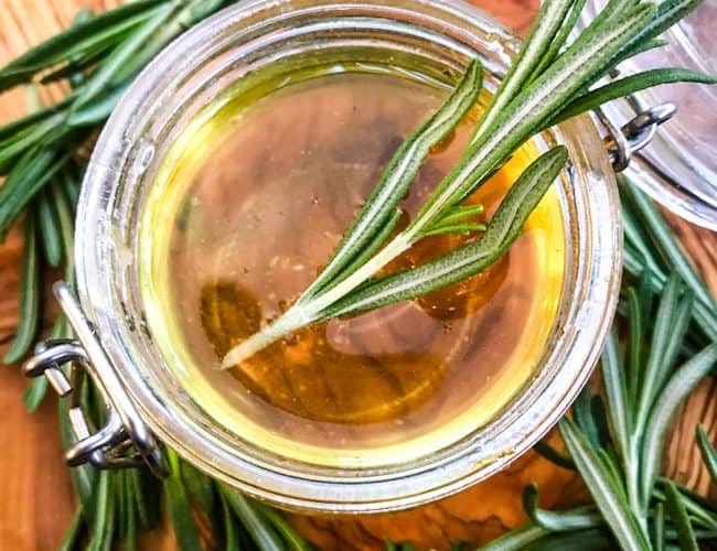 Some Rosemary Simple Syrup in a jar with rosemary around it