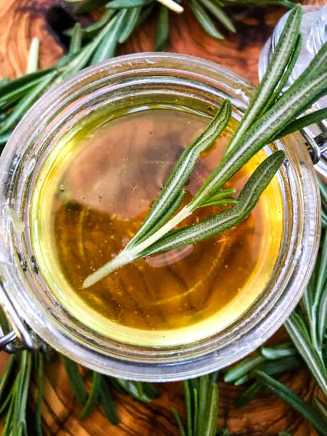 Close top view of the liquid in a jar with herbs in and around it