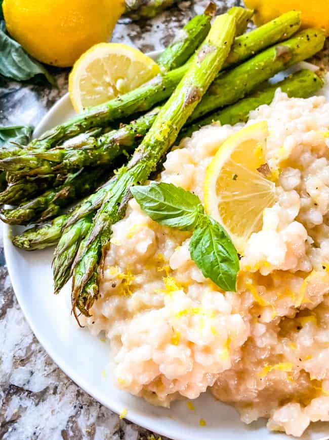 A round white plate with Risotto al Limone (Lemon Risotto) and asparagus
