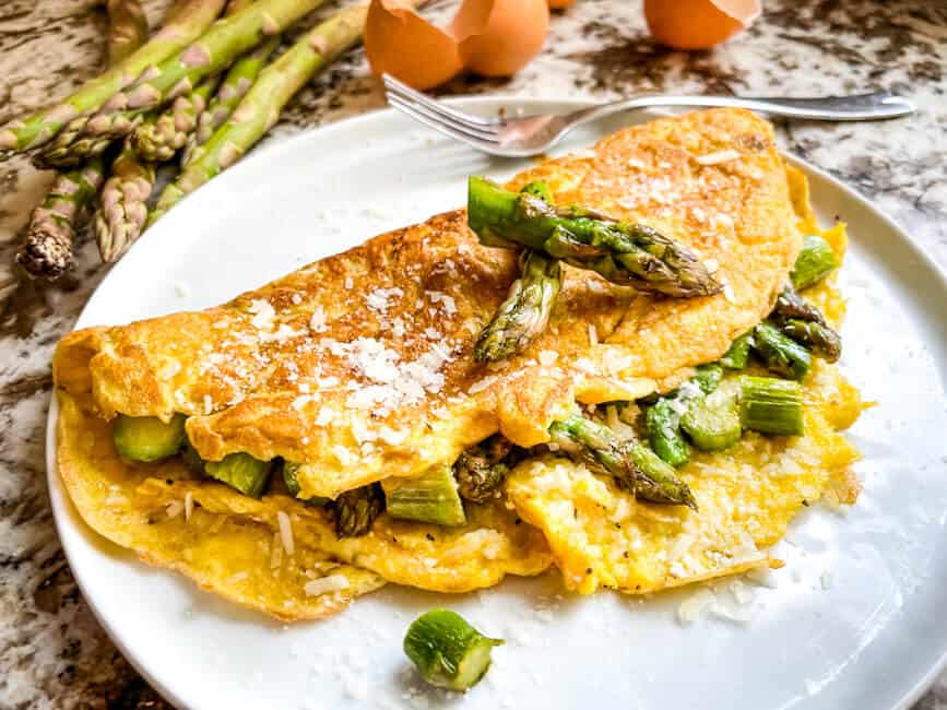 Asparagus Omelette topped with vegetables on a white plate