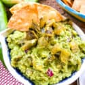 A bowl of Hatch Green Chile Guacamole with some chips sticking out of it