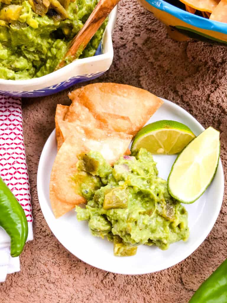 A plate with some dip, chips, and limes