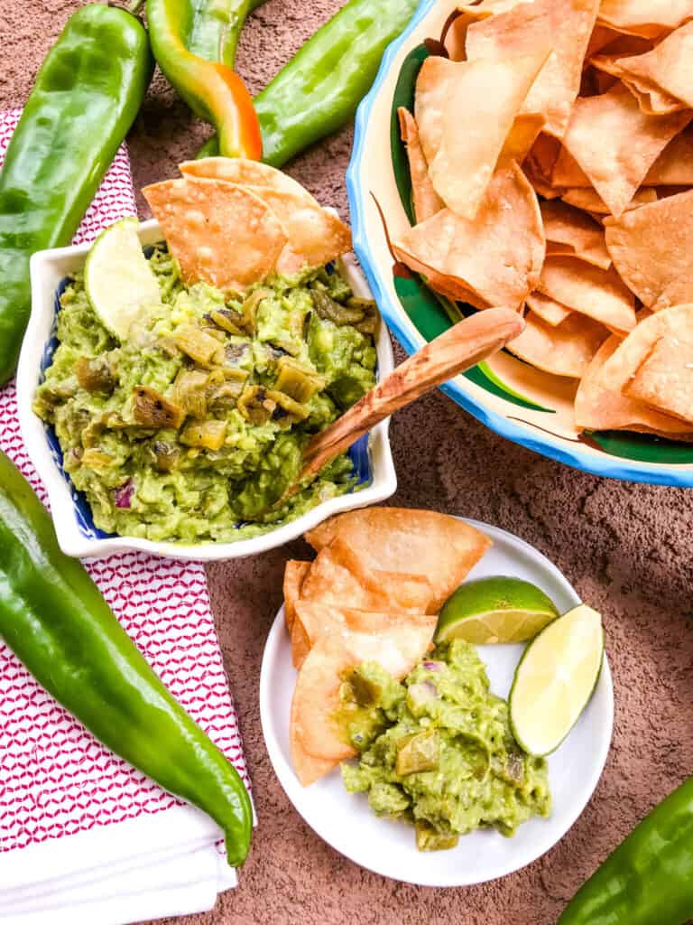 A spread of Hatch Green Chile Guacamole in a bowl with chips and a plate being served up