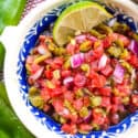 Close up of Hatch Green Chile Pico de Gallo in a white and blue bowl with a lime wedge