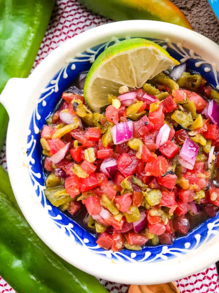 Close up of Hatch Green Chile Pico de Gallo in a white and blue bowl with a lime wedge