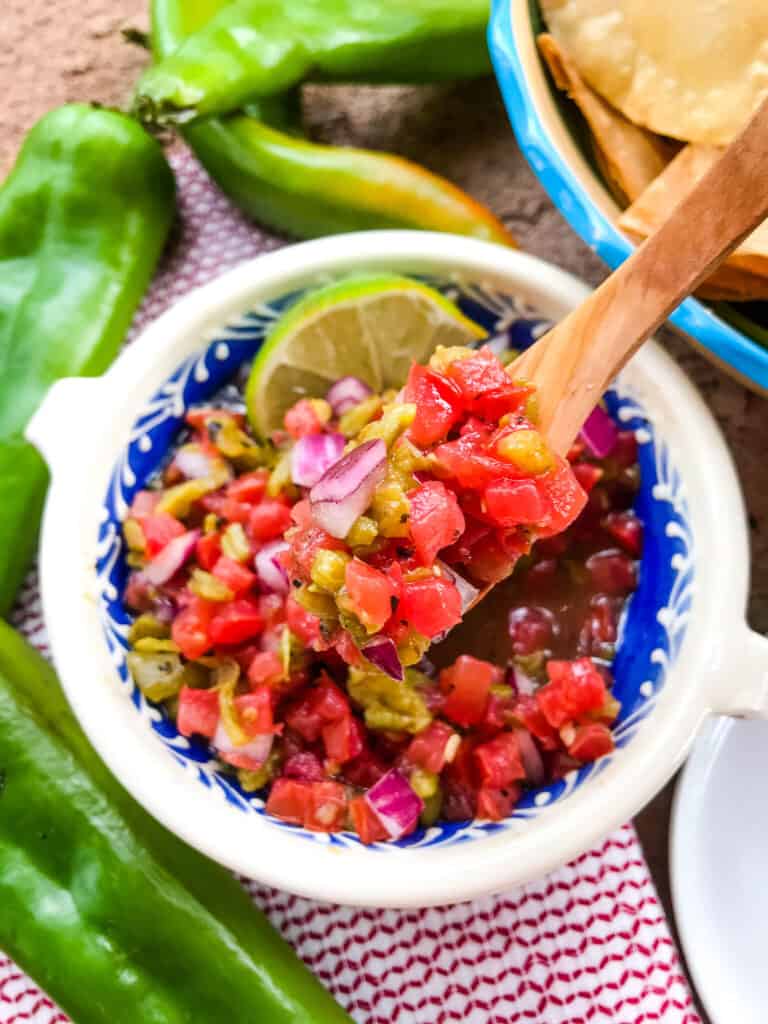 A spoon scooping Hatch Green Chile Pico de Gallo out of a bowl