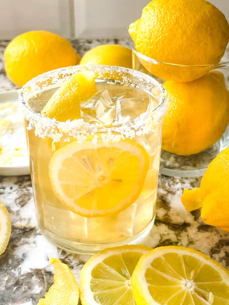 A yellow tequila cocktail surrounded by fruit