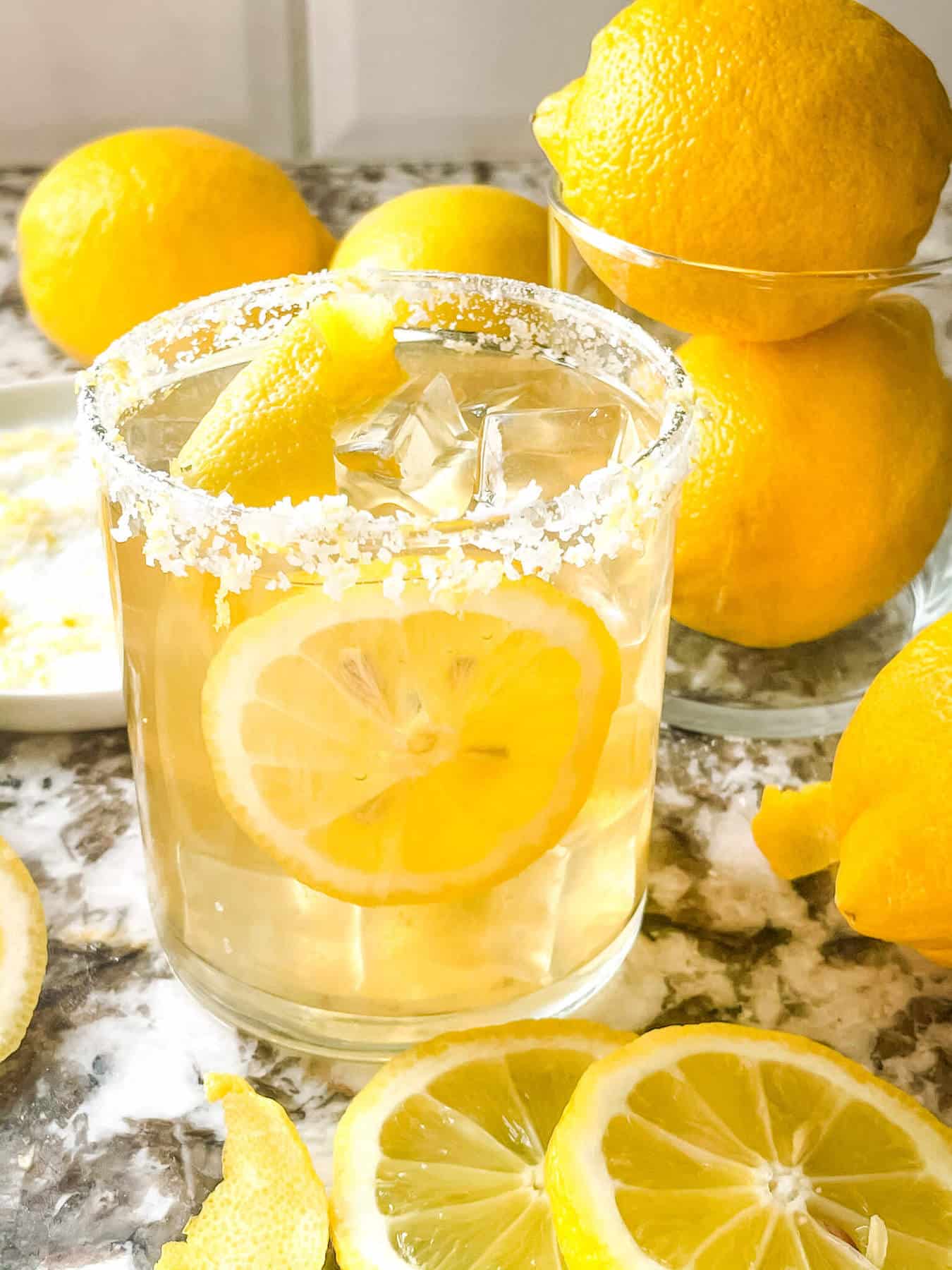 A yellow tequila cocktail surrounded by fruit