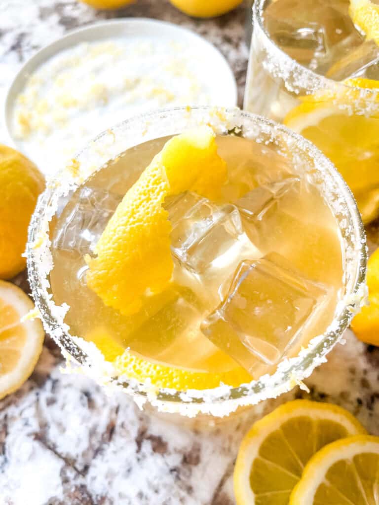 Top view of a glass of Lemon Margarita with a salt rim and lemon peel in it