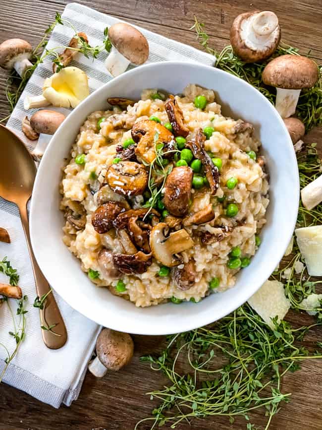 A white bowl full of the rice dish from the top with mushrooms around it