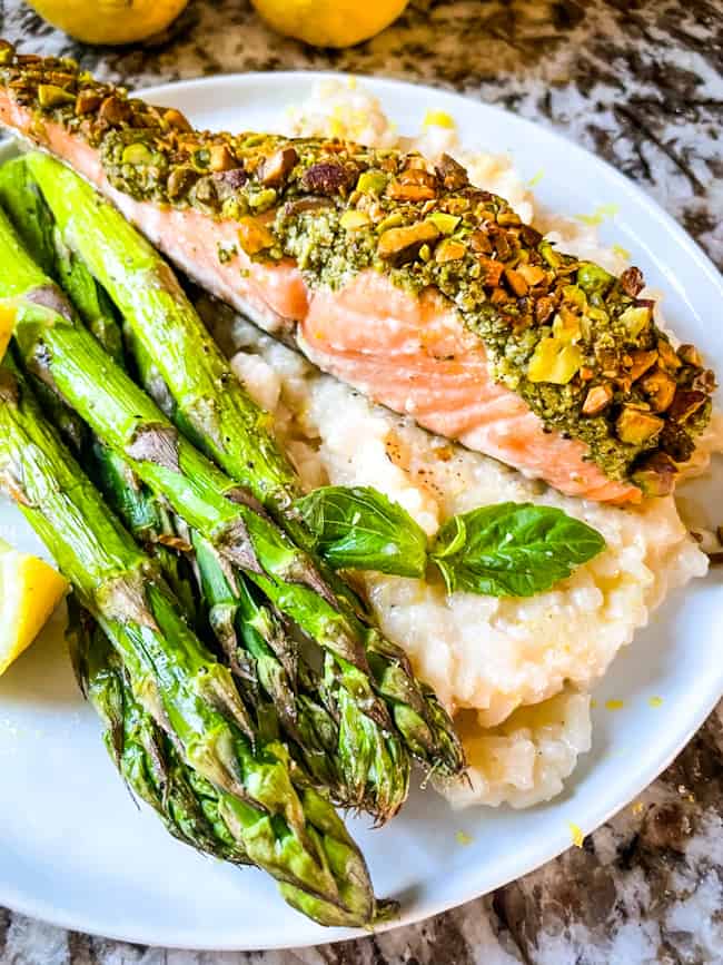 Pesto Crusted Salmon on a bed of risotto al limone with air fryer asparagus on a plate