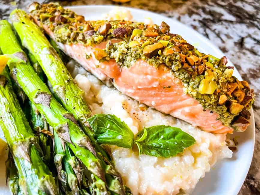 Pesto Crusted Salmon on a bed of Risotto al limone with air fryer asparagus on a plate