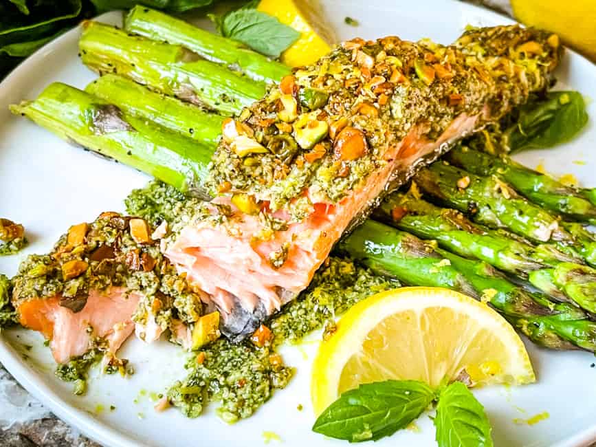 Pesto Crusted Salmon partially eaten on top of asparagus