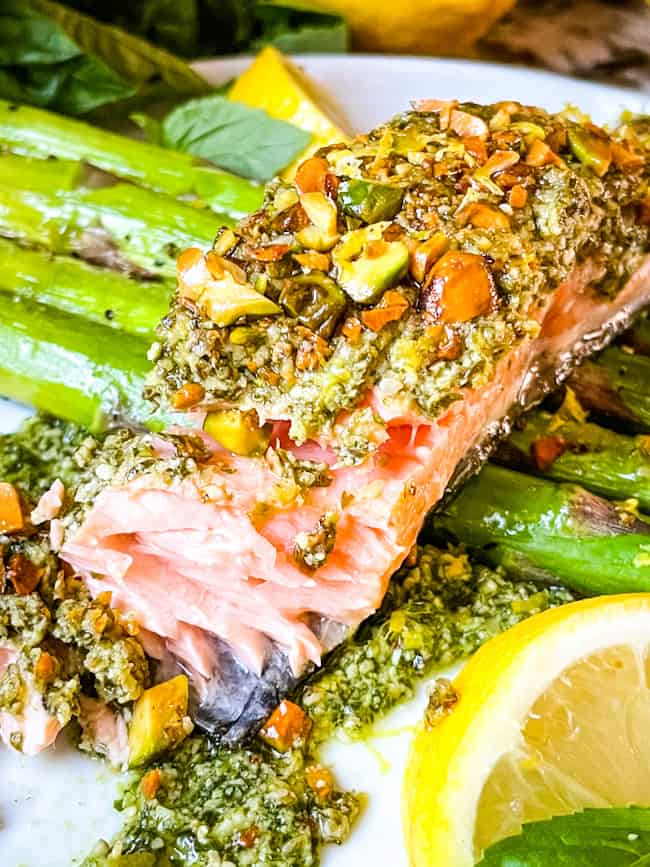 Pesto Crusted Salmon partially eaten on top of asparagus