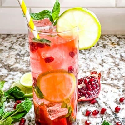 One tall glass of Pomegranate Mojito with limes and pomegranate seeds