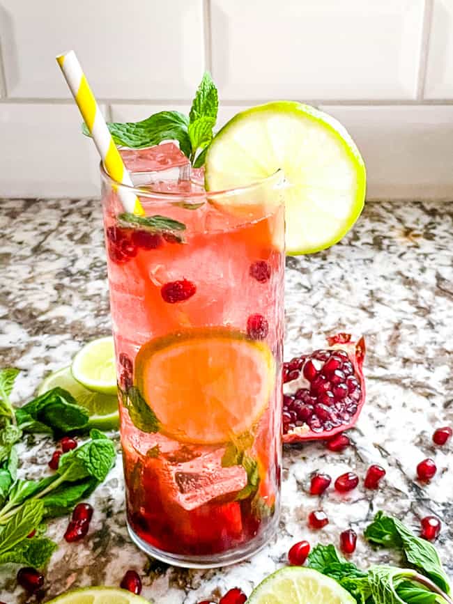 One tall glass of Pomegranate Mojito with limes and pomegranate seeds