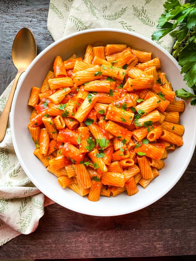A large bowl filled with Rigatoni Arrabbiata on a wood surface
