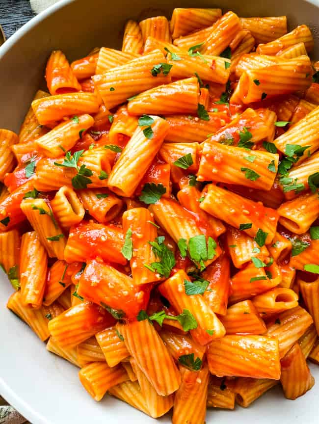 A close up of pasta with red sauce and parsley