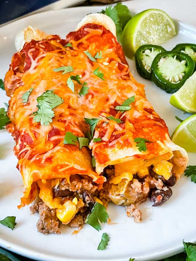 Two Southwest Ground Turkey Enchiladas on a plate with cilantro and limes