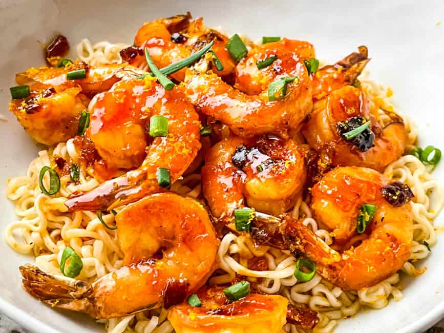 A pile of Chipotle Orange Glazed Shrimp on a bed of noodles in a bowl