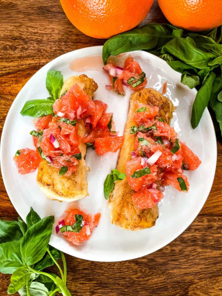 Top view of two pieces of Cod with Grapefruit Relish on a white plate