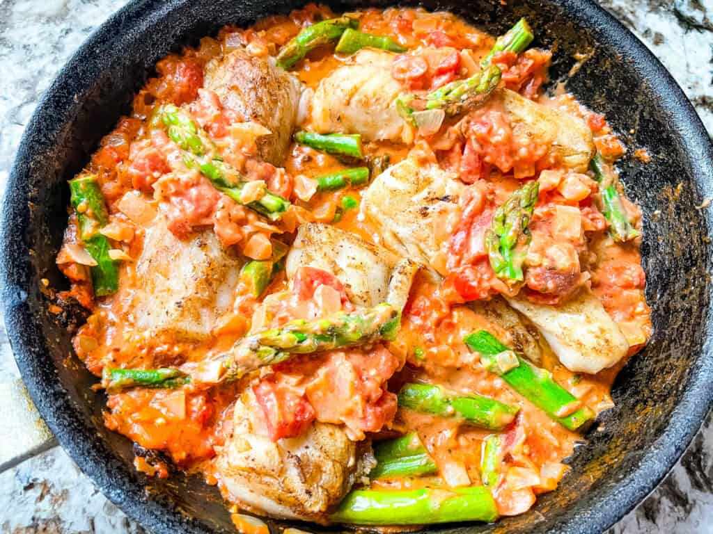 Top view of Cod Pomodoro with Asparagus in a skillet