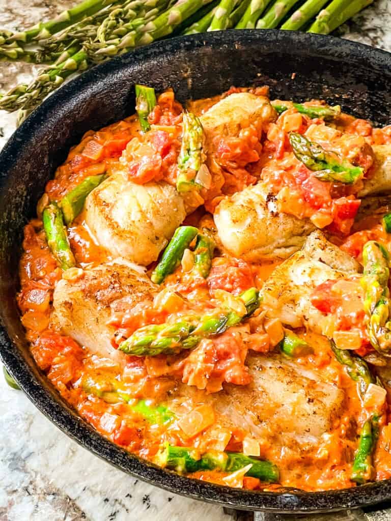 Cod Pomodoro with Asparagus in a black skillet