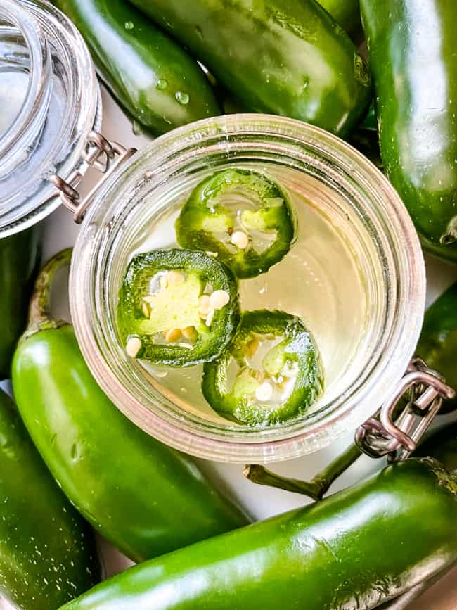 Top view of Jalapeno Simple Syrup in a jar with jalapenos around it