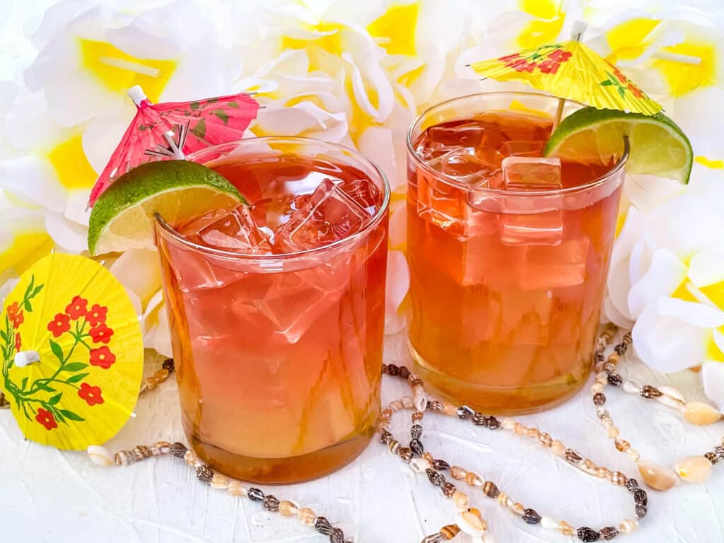 Two Malibu Bay Breeze cocktails with umbrellas, shells, and flowers