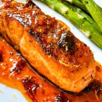 A cooked Chipotle Orange Glazed Salmon steak with sauce under it on a plate