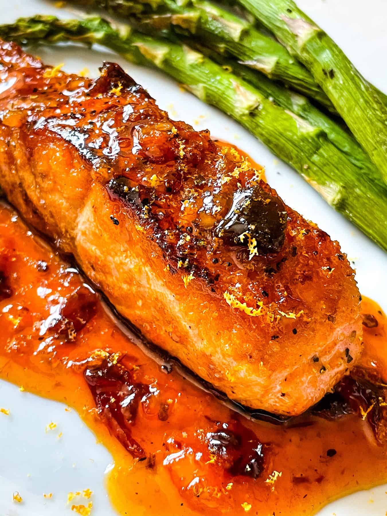 A cooked Chipotle Orange Glazed Salmon steak with sauce under it on a plate