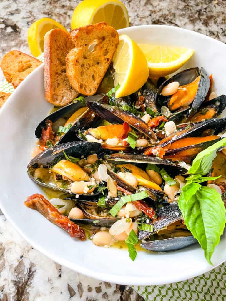 Copycat Maggiano's Tuscan Mussels in a white bowl with lemons and bread
