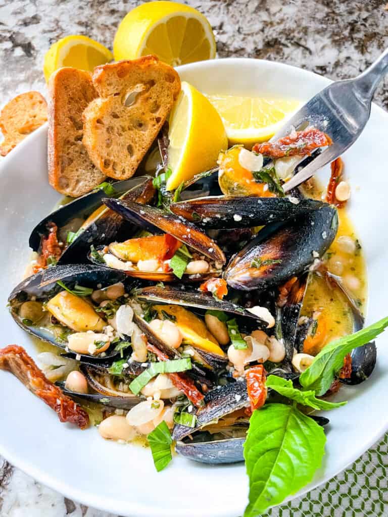 A fork digging into a bowl of Copycat Maggiano's Tuscan Mussels