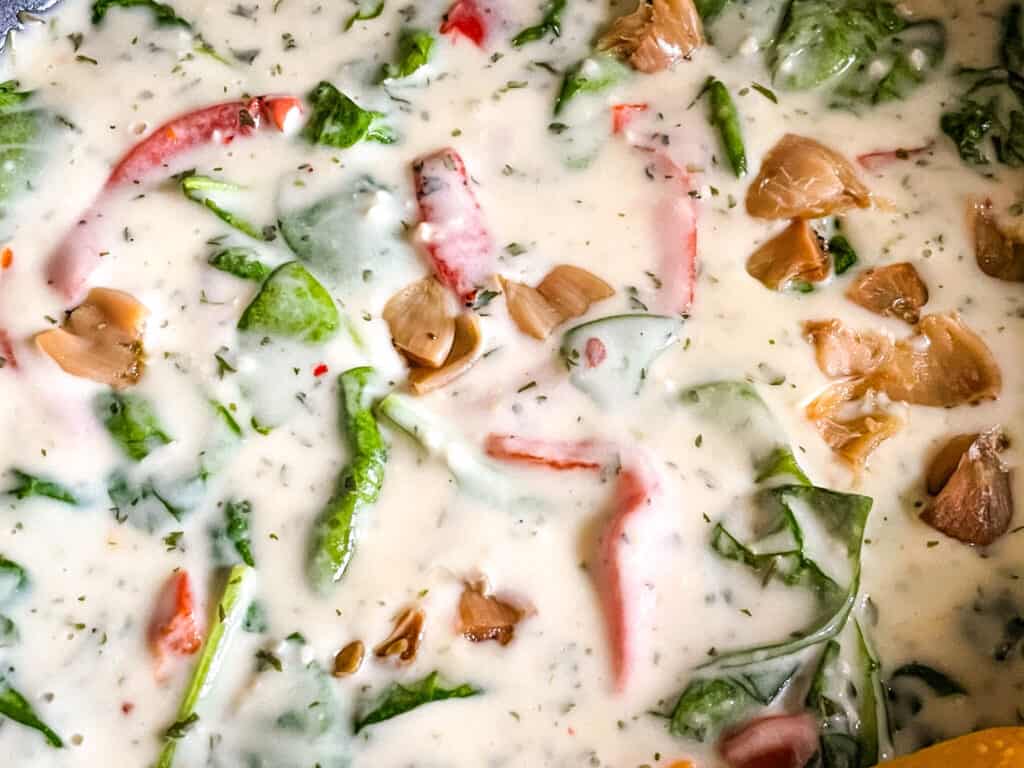 The creamy sauce with vegetables being cooked