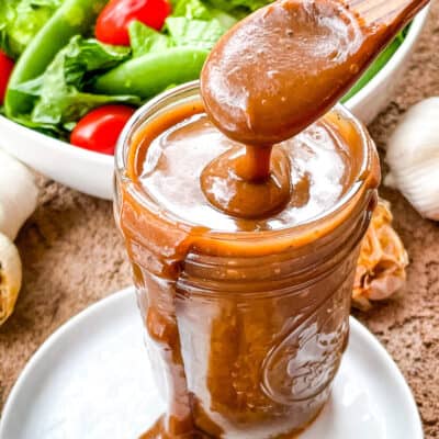 A spoon scooping some Creamy Balsamic Dressing out of the jar