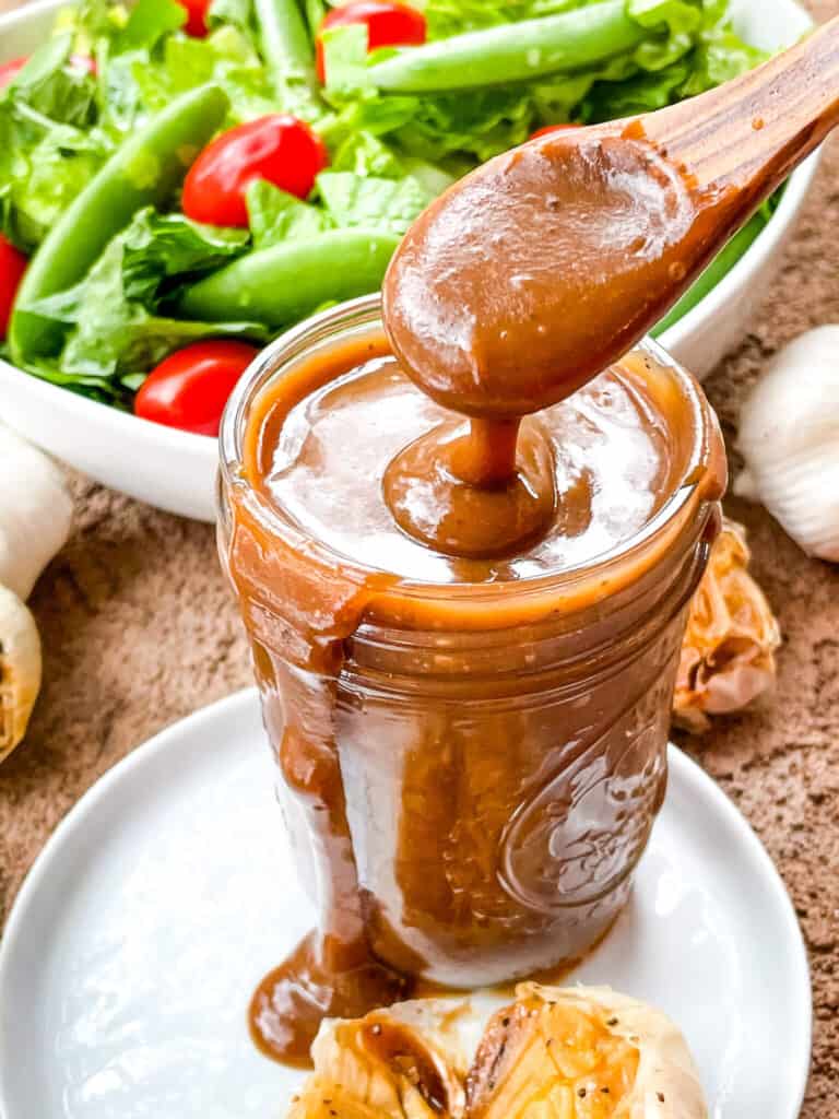 A spoon scooping some Creamy Balsamic Dressing out of the jar