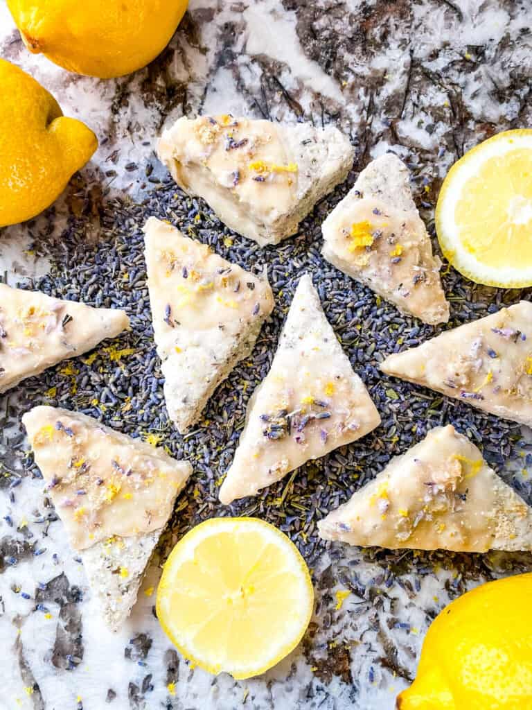 Lemon Lavender Shortbread Cookies scattered across lavender buds with lemon pieces