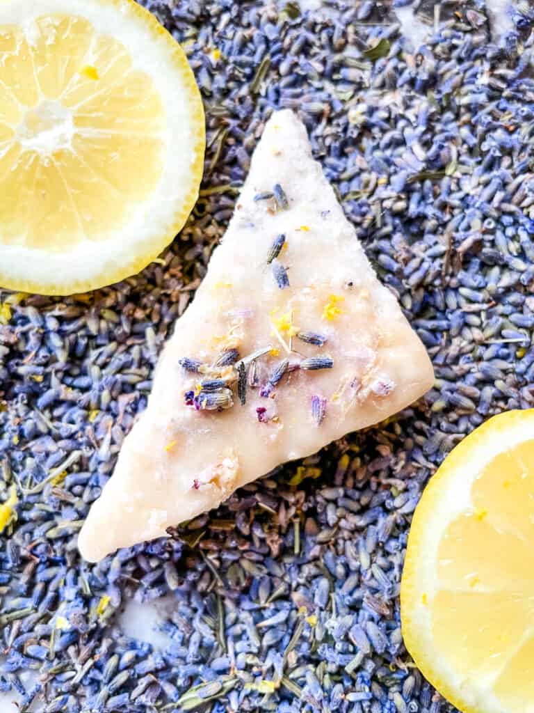 A lavender cookie on top of lavender buds with lemon slices