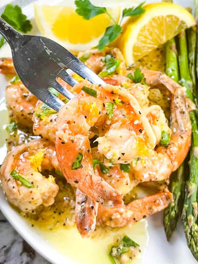 A fork holding a Lemon Pepper Shrimp above the plate