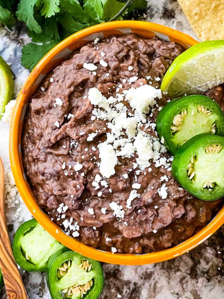 The mashed beans in a bowl with peppers on top