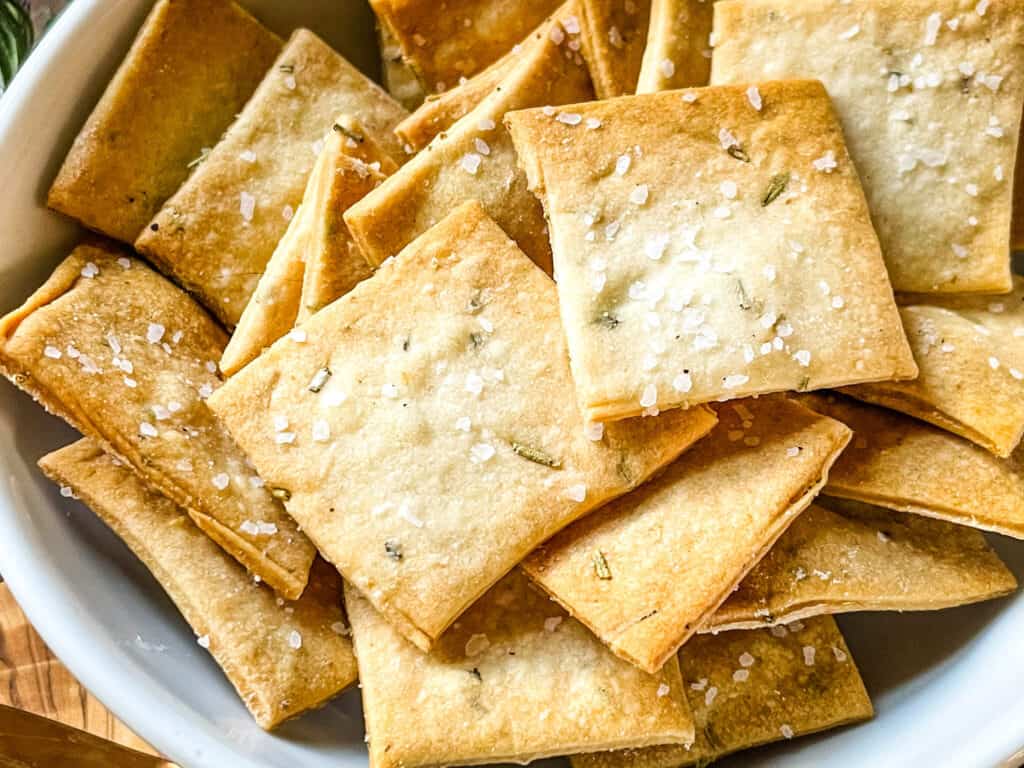 Close up of Rosemary Sourdough Crackers in a white bowl
