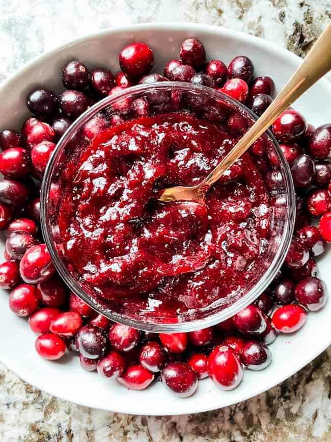 Top view of the condiment with a spoon nestled inside a large bowl full of fresh berries